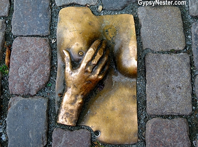 Brass hand fondling a woman's breast in the cobblestones near the Old Church in Amsterdam, Holland