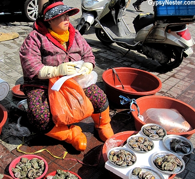 A woman sits outside the fish market in Busan, South Korea