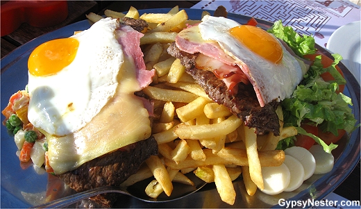 Chivito Gigante! Two huge hunks of cow, slices of ham, slabs of bacon, pounds of potatoes, and a veritable garden, all topped off with a couple fried eggs. 