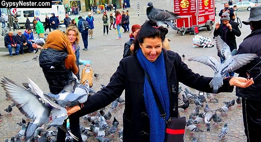Veronica plays with pigeons in Dam Square, Amsterdam, Holland. GypsyNester.com