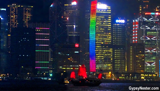 A traditional Chinese junk sets sail in Victoria Harbor amid Hong Kong's modern skyscrapers