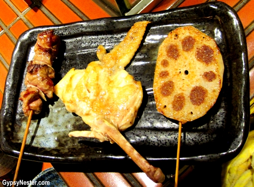 beef kalbi (ribs), chicken wing, and lotus root stuffed with shitaki mushrooms on a stick on Osaka Japan