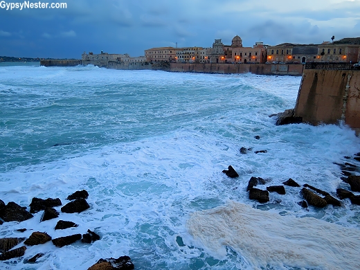 Waves crashing against Castello Maniace in Syracuse, Sicily, Italy