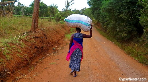  Une femme porte un sac lourd sur la tête dans le village de Rau, près de Moshi, en Tanzanie. Avec Discover Corps.