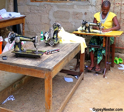 Une femme coud dans une cour du village de Rau en Tanzanie, en Afrique, avec Discover Corps 